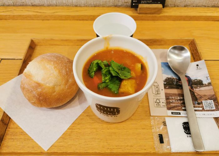 A cup of soup and a fresh bread roll at Soup Stock Tokyo.